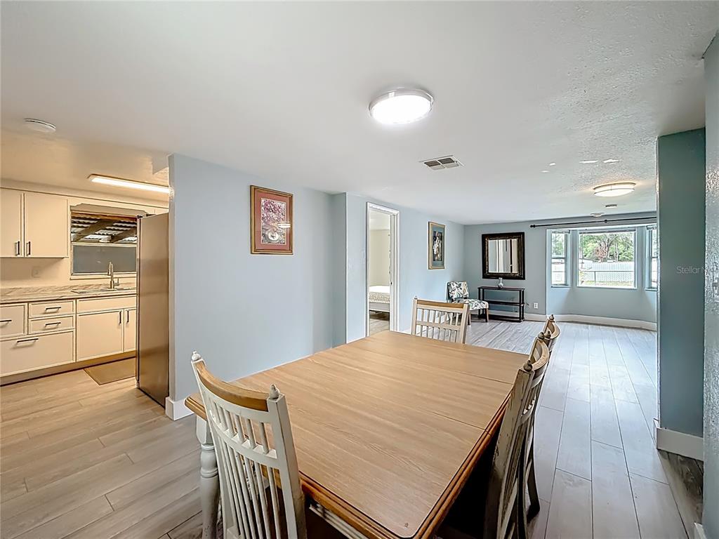 A dining area with a wooden table and chairs adjacent to a kitchen and living room — 544 MERCURY AVENUE, ORLANDO, FL