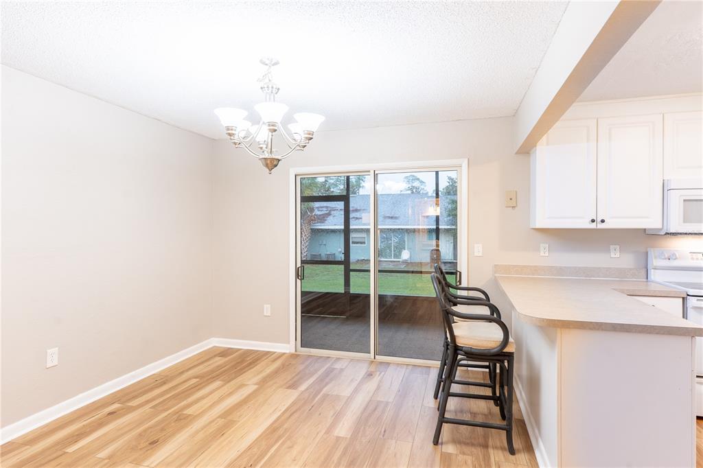 A dining area with wood-look flooring, a chandelier, and a sliding glass door to a patio — 501 SW 75TH STREET UNIT D13, GAINESVILLE, FL