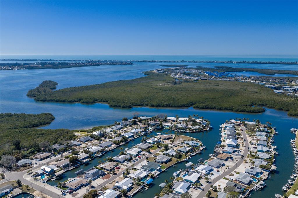 An aerial view shows a waterfront residential neighborhood surrounded by mangroves and the ocean — 10316 KINGFISHER ROAD W, BRADENTON, FL