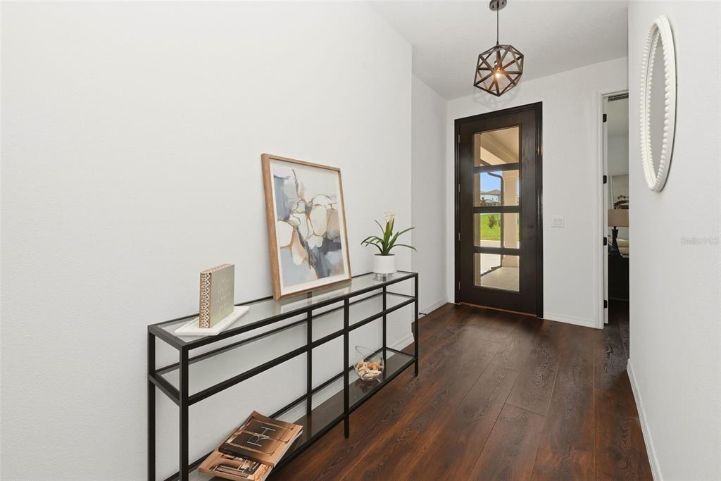 An entryway features a dark wood front door, a glass console table, and hardwood floors — 2346 GOLD DUST DRIVE, MINNEOLA, FL