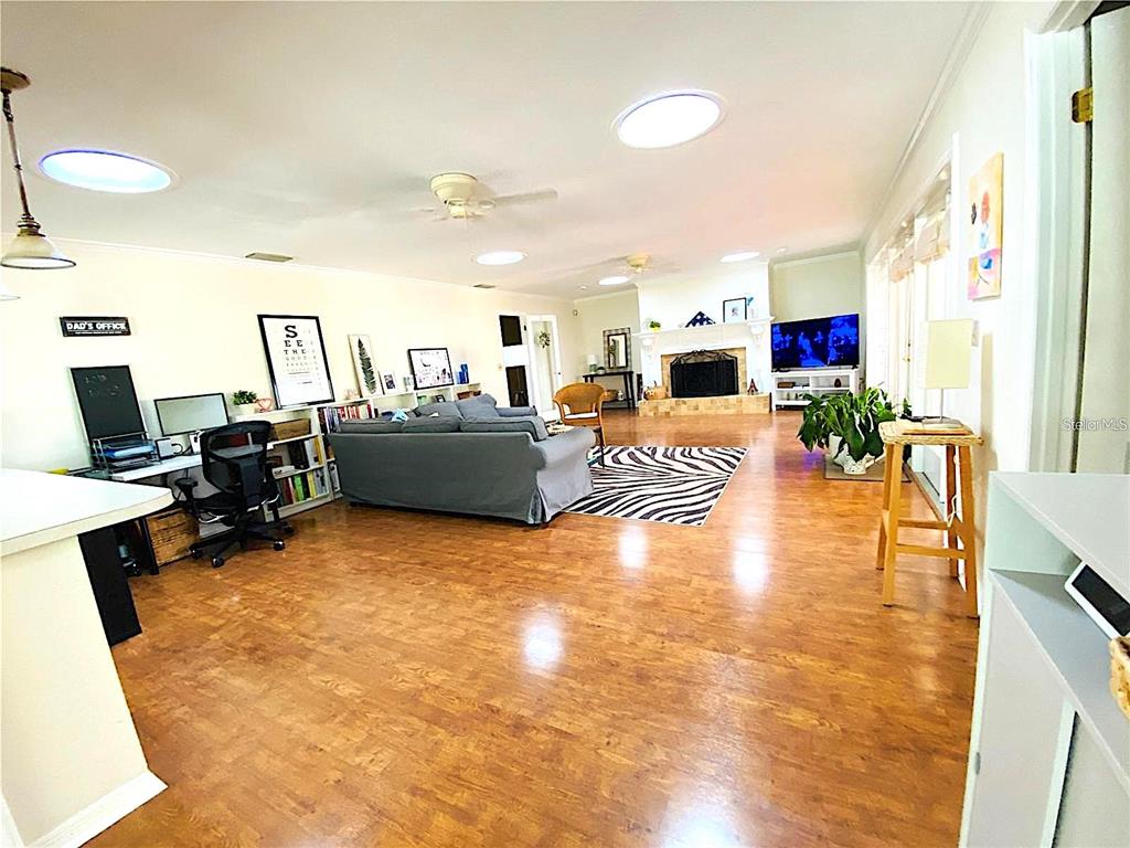 A spacious living room features wood-look flooring, a fireplace, and a dedicated office area — 1449 ERROL PARKWAY, APOPKA, FL