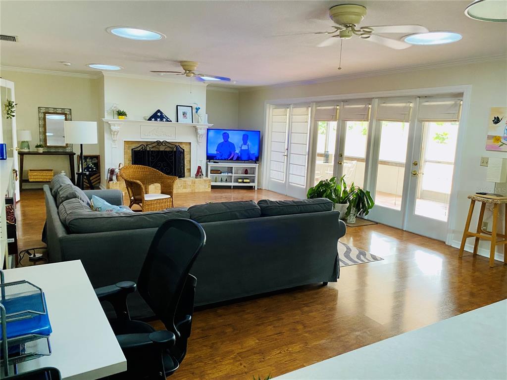 A room with hardwood floors features a wall of glass doors leading to a screened porch — 1449 ERROL PARKWAY, APOPKA, FL