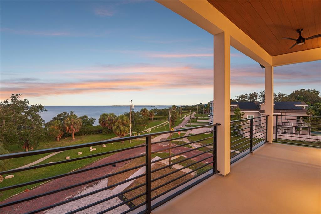 A balcony with a black metal railing overlooks a coastal park and the ocean — 96 SHORE DRIVE, TARPON SPRINGS, FL