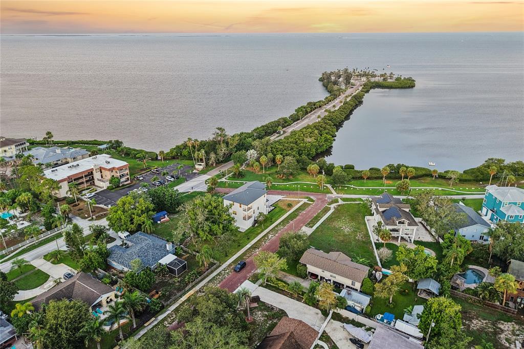 An aerial view shows a coastal neighborhood with houses, palm trees, and a long causeway — 96 SHORE DRIVE, TARPON SPRINGS, FL