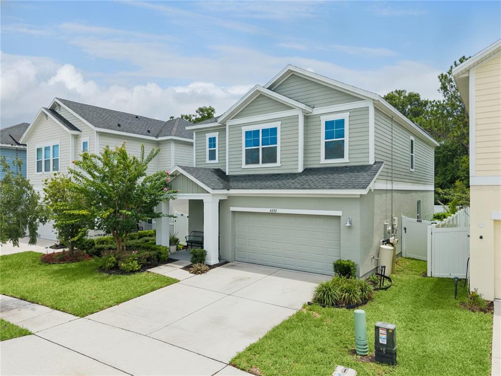 A two-story house with light green siding, a two-car garage, and a front porch — 4222 HIBISCUS BLOOM DRIVE, ORLANDO, FL