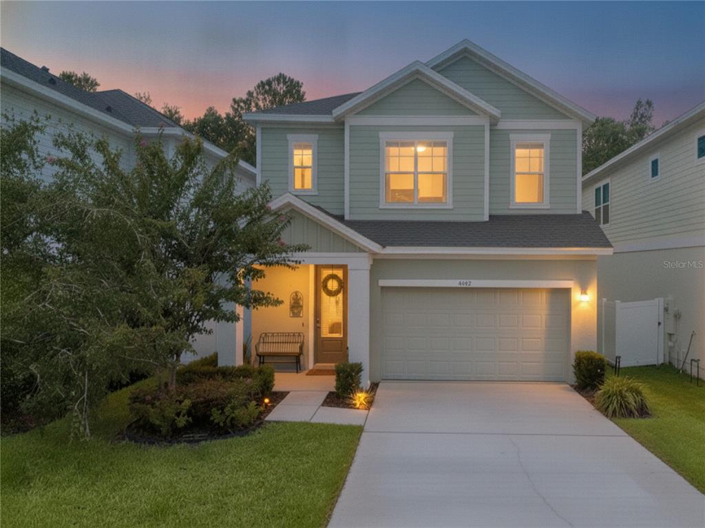 A two-story house with light green siding, a front porch, and an attached two-car garage — 4222 HIBISCUS BLOOM DRIVE, ORLANDO, FL