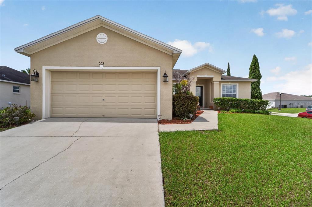 A single-story house with a beige stucco exterior, a two-car garage, and a front lawn — 603 POINTER LANE, LAKELAND, FL