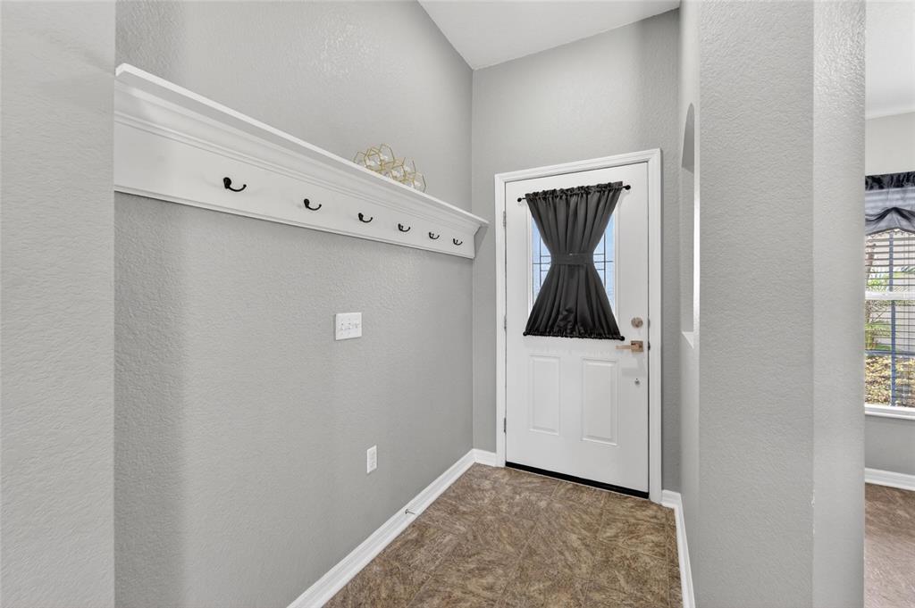 An entryway features a white door with a black curtain, a coat rack, and tile flooring — 603 POINTER LANE, LAKELAND, FL
