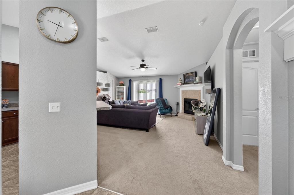 A living room features a fireplace, a ceiling fan, and a large wall clock — 603 POINTER LANE, LAKELAND, FL