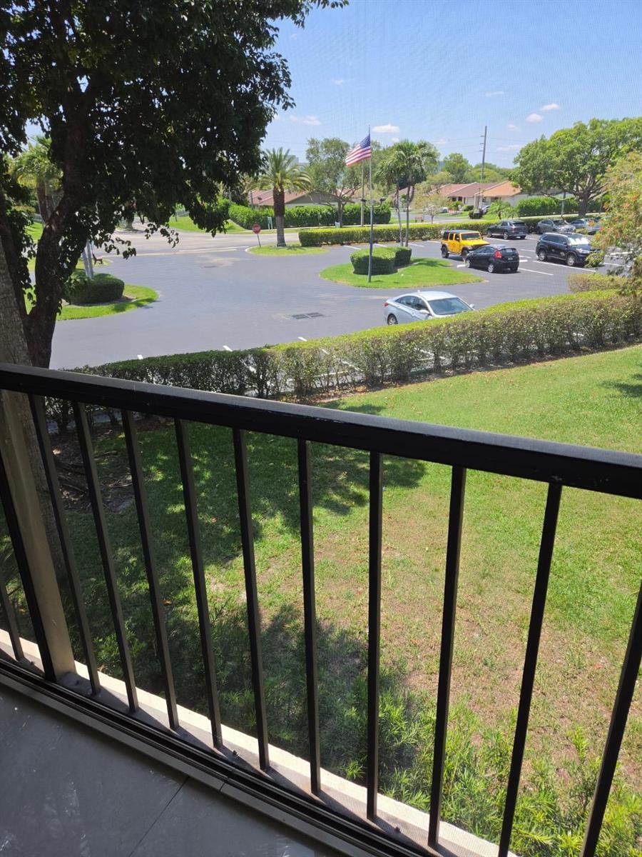 A view from a balcony overlooking a parking lot, green lawn, and trees — 5310 Las Verdes Circle # 220, Delray Beach FL 33484, DELRAY BEACH, FL