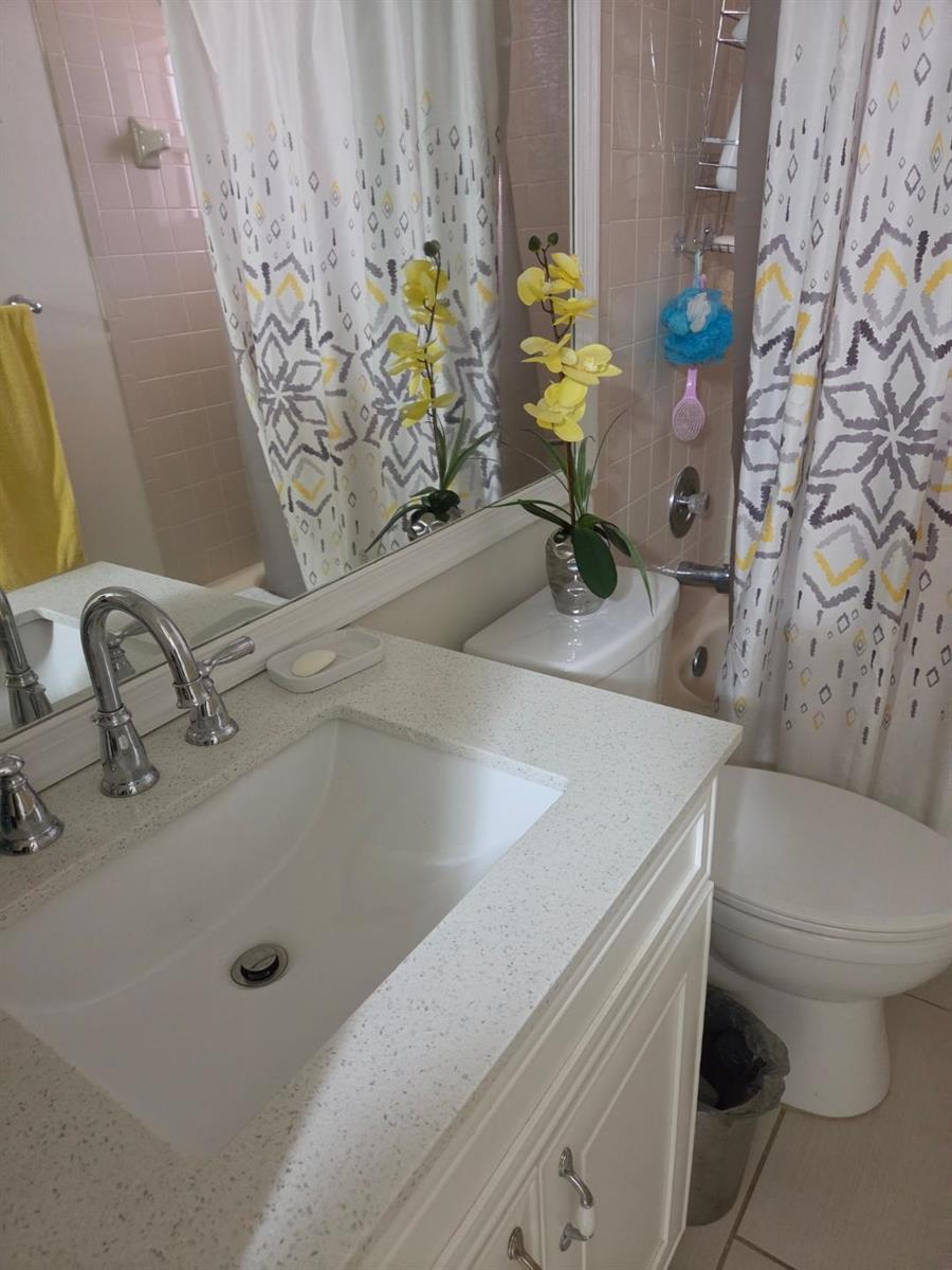A bathroom features a white vanity with a speckled countertop, a toilet, and a shower — 5310 Las Verdes Circle # 220, Delray Beach FL 33484, DELRAY BEACH, FL