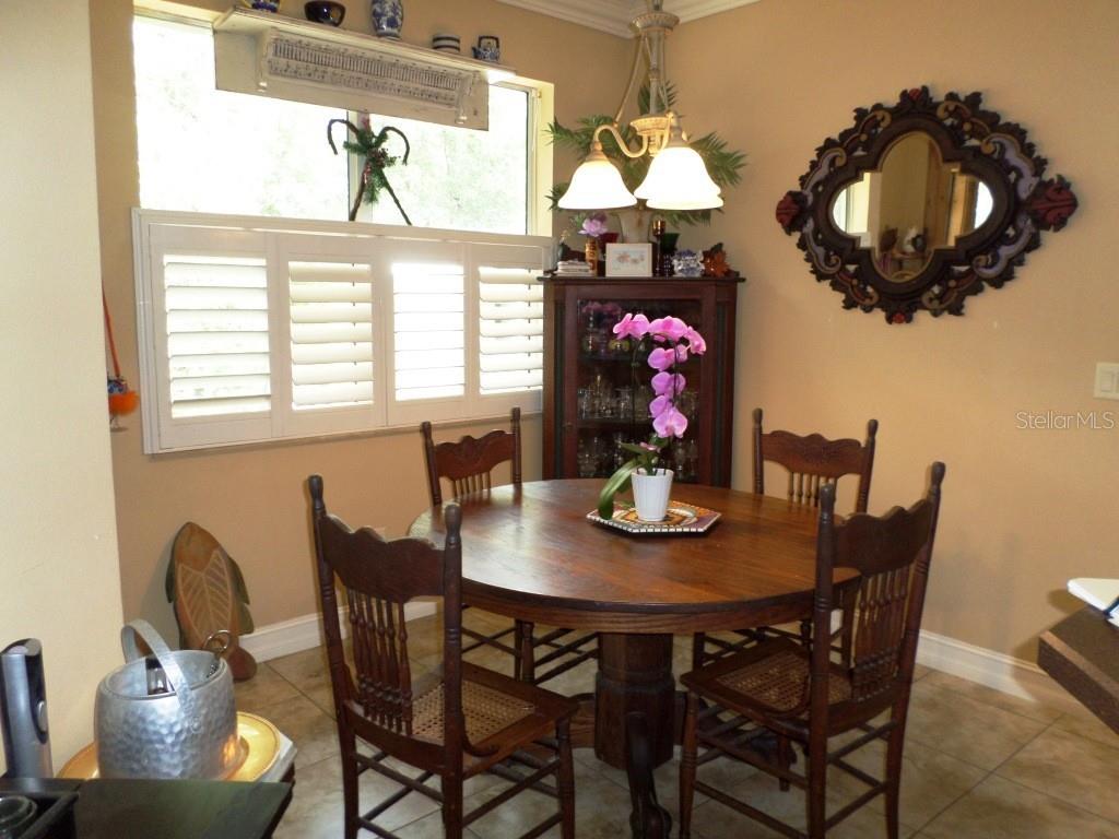 A dining area features a round wooden table, four chairs, a hutch, and a wall mirror — 9419 N COUNTRY CLUB WAY, DUNNELLON, FL