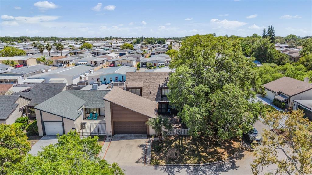 An aerial view shows a house with a brown roof and garage next to trees — 7300 BELLOWS FALLS LANE, HUDSON, FL