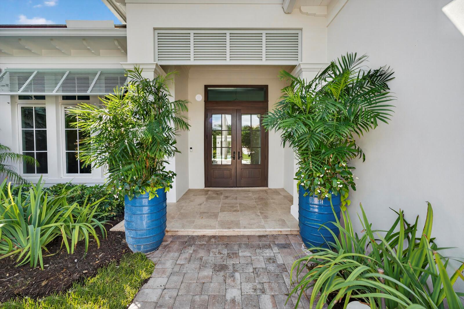 The front entrance features a double wood door, two large blue planters, and stone pavers — 544 Live Oak Road, Vero Beach FL 32963, VERO BEACH, FL