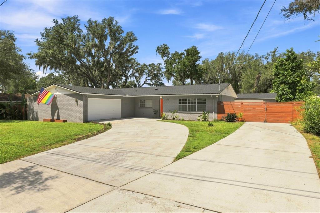 A single-story gray brick house with a concrete driveway and a wooden fence — 216 AMANA AVENUE, BRANDON, FL