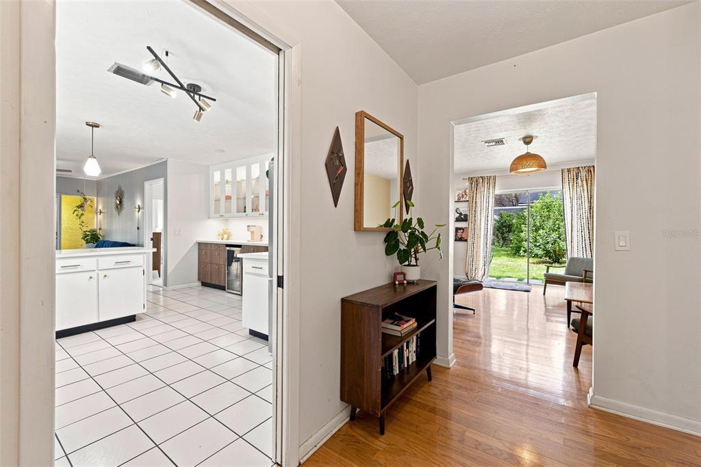 A hallway with wood flooring leads to a kitchen on the left and living area — 216 AMANA AVENUE, BRANDON, FL