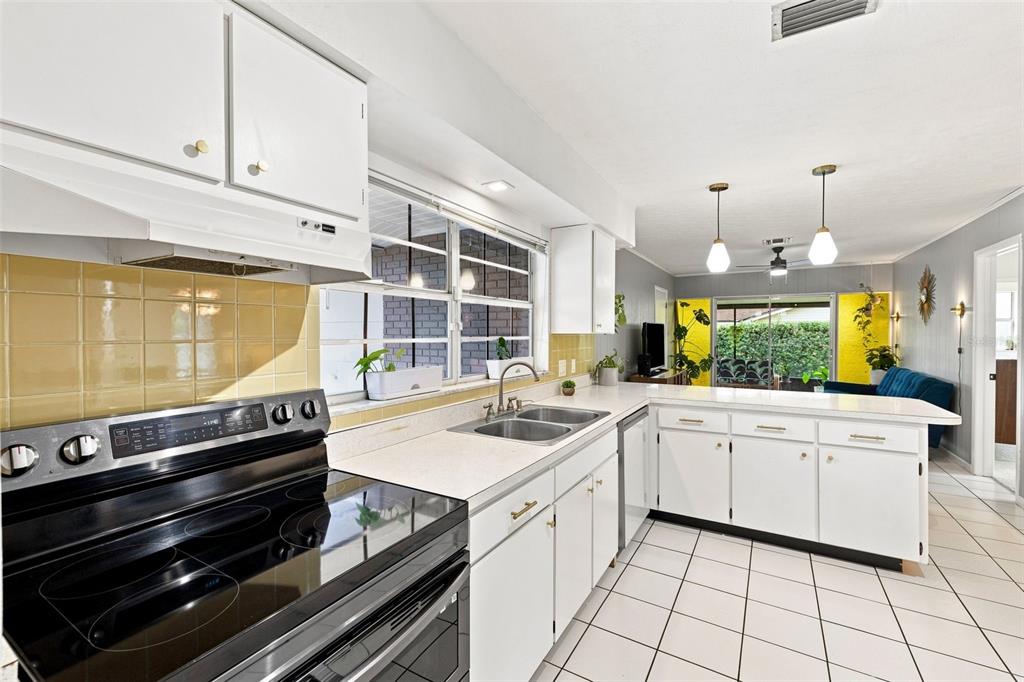 A kitchen with white cabinets, yellow tile backsplash, and a black electric range — 216 AMANA AVENUE, BRANDON, FL