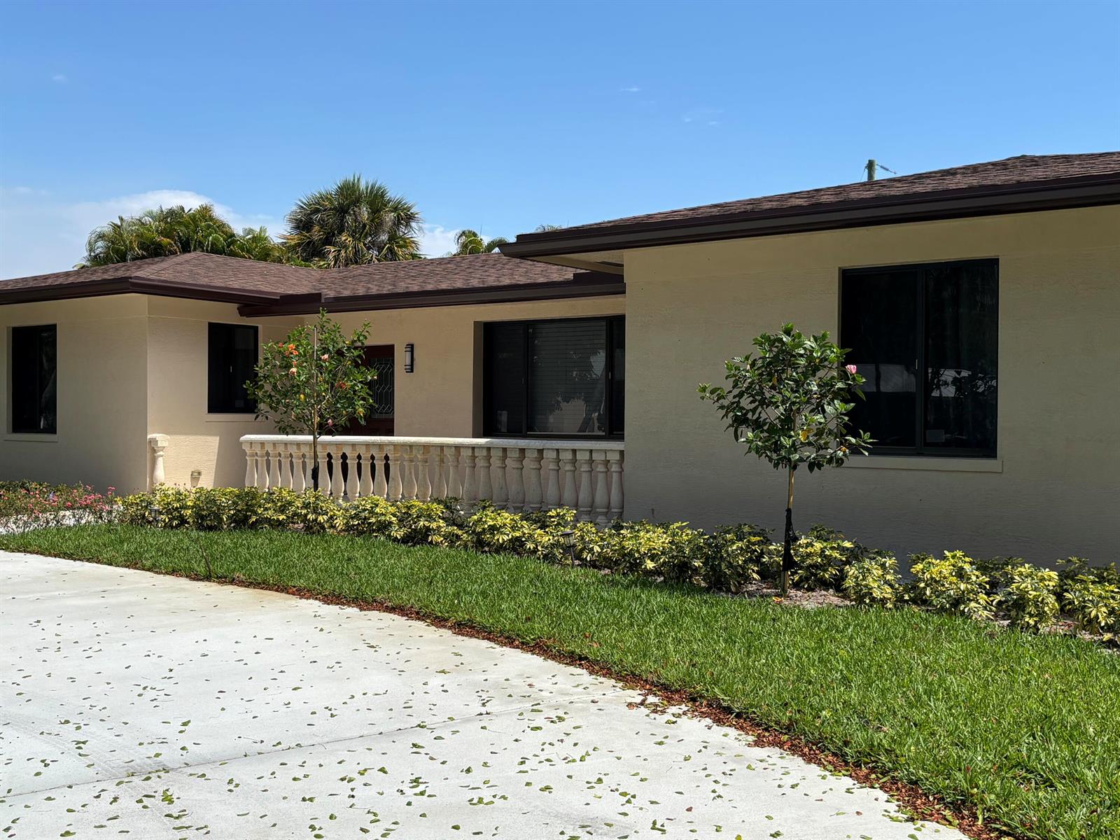 A single-story house with a beige exterior, dark roof, and a front stone balustrade — 135 E Ilex Drive, Lake Park FL 33403, LAKE PARK, FL