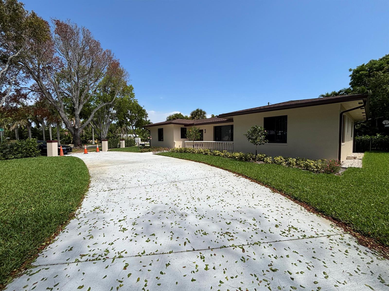 A single-story house with a concrete driveway and a manicured lawn under a clear sky — 135 E Ilex Drive, Lake Park FL 33403, LAKE PARK, FL