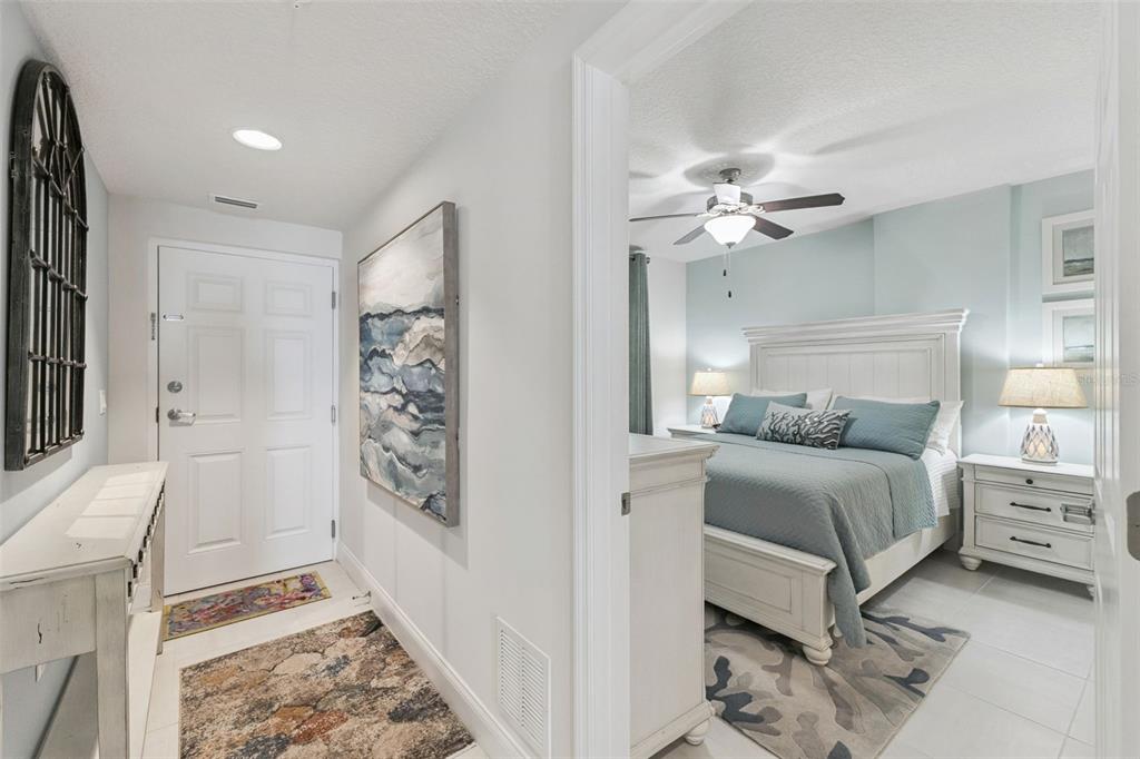 A white entryway leads into a bedroom featuring a white bed frame and blue bedding — 3721 S ATLANTIC AVENUE UNIT 1004, DAYTONA BEACH, FL