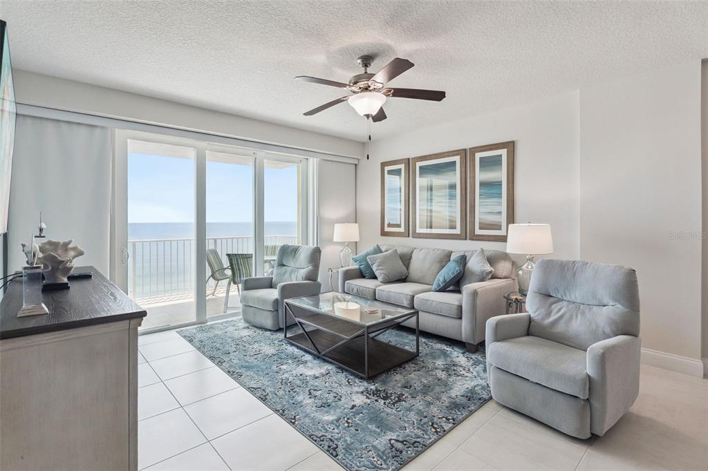 A living room features a sofa, two armchairs, a coffee table, and a balcony view — 3721 S ATLANTIC AVENUE UNIT 1004, DAYTONA BEACH, FL