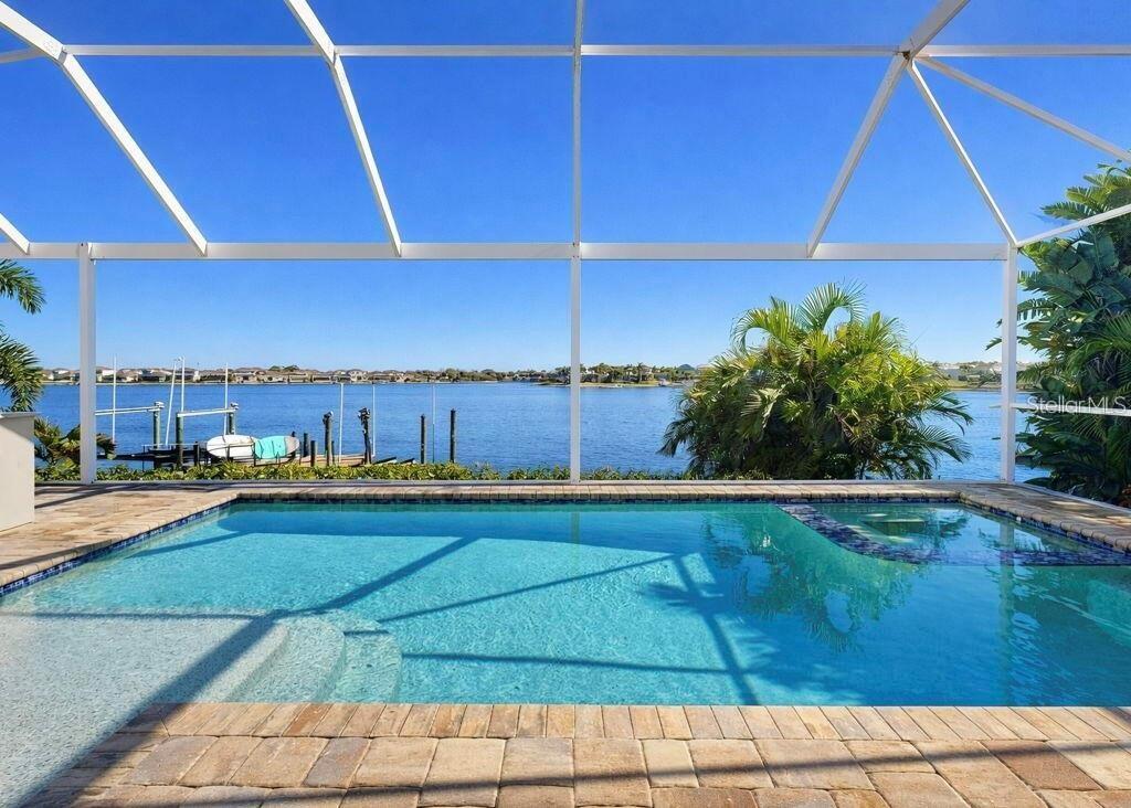 A screened-in swimming pool overlooks a wide canal with a private boat dock — 5237 BRIGHTON SHORE DRIVE, APOLLO BEACH, FL