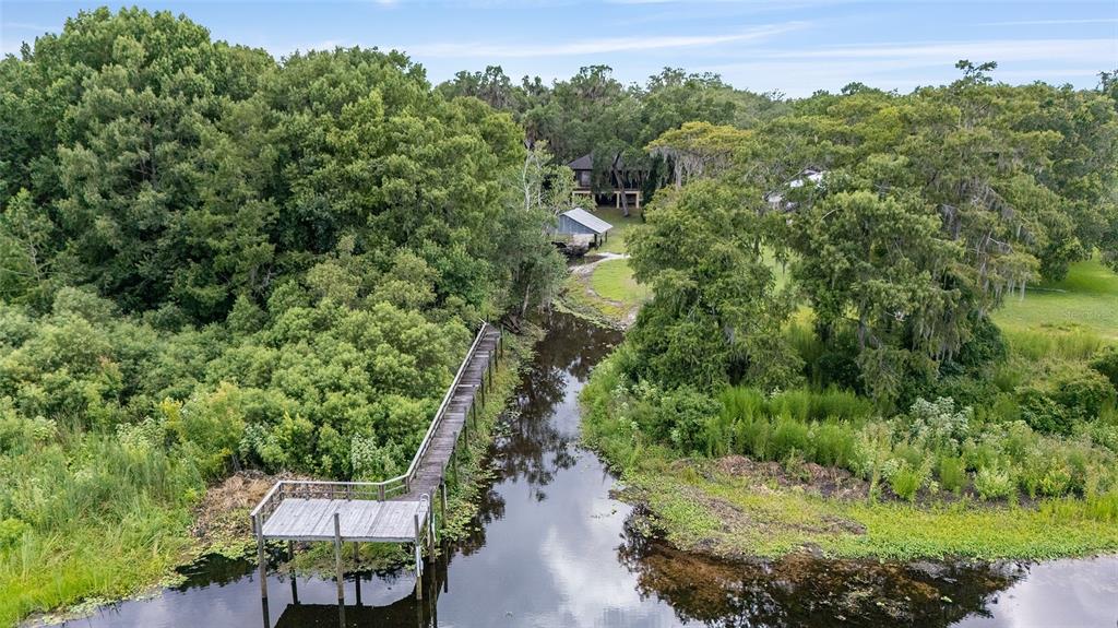 An aerial view shows a wooden dock extending into a narrow waterway near a house — 2299 N BAYOU POINT, INVERNESS, FL