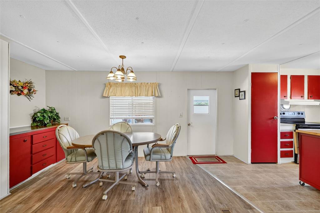 A dining area with a round table, swivel chairs, red cabinets, and wood-look flooring — 563 TAMMI DRIVE, LEESBURG, FL