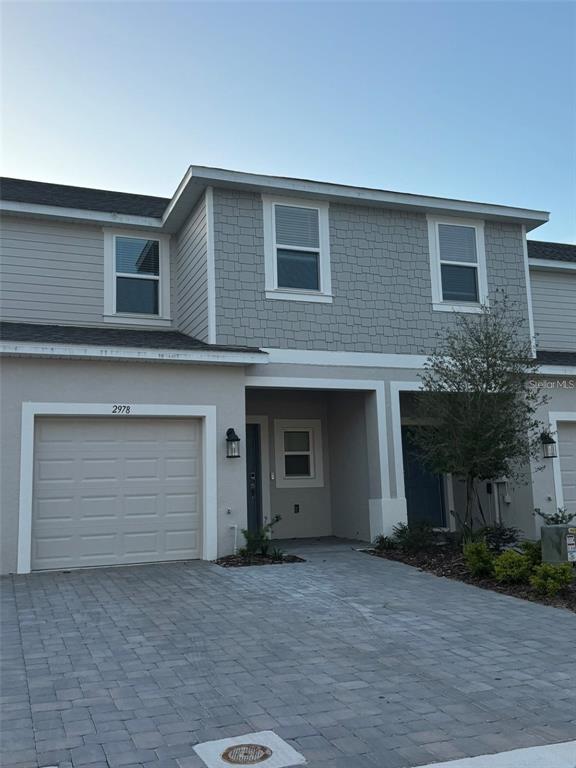 A two-story townhouse exterior with a single-car garage, gray siding, and a paved driveway — 2978 CANARY AVENUE, DAVENPORT, FL