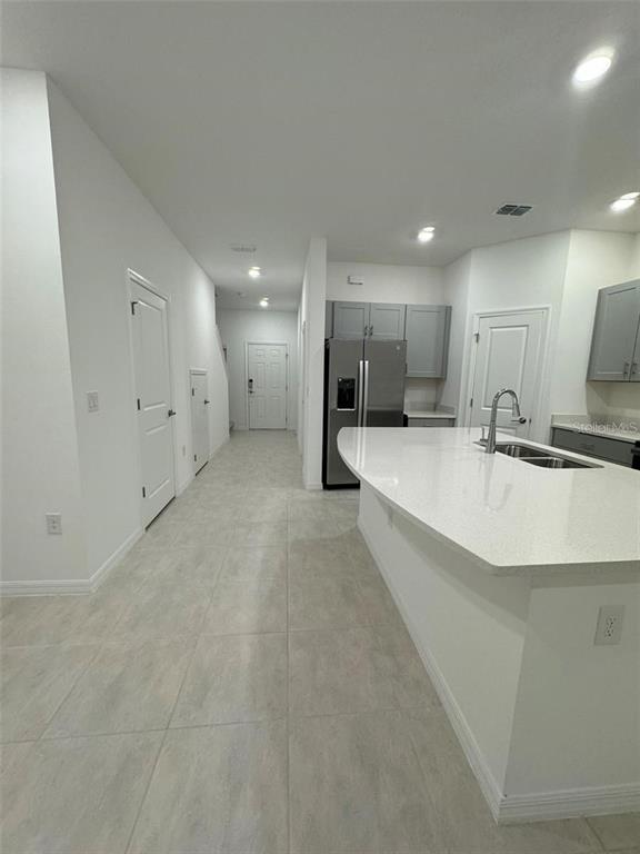 A kitchen features a white quartz island, stainless steel appliances, and light tile flooring — 2978 CANARY AVENUE, DAVENPORT, FL