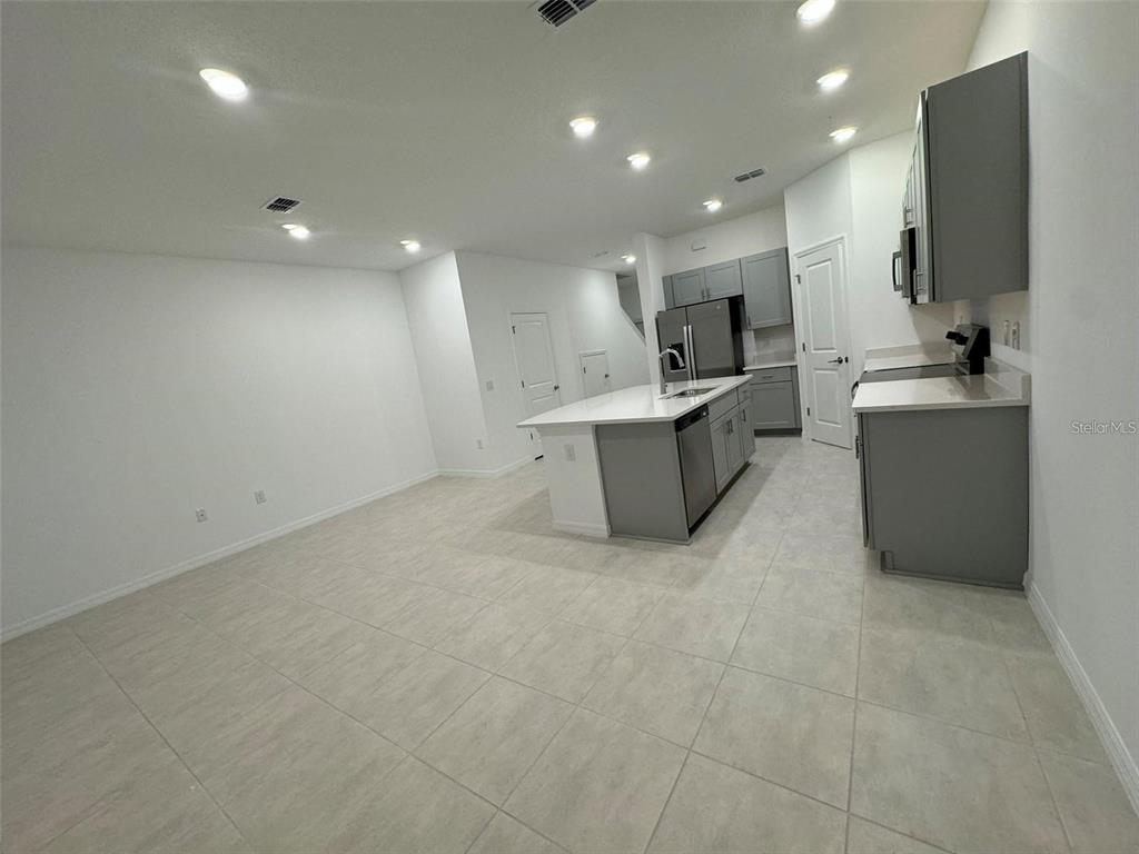 A modern kitchen features a central island, grey cabinetry, stainless steel appliances, and tile flooring — 2978 CANARY AVENUE, DAVENPORT, FL
