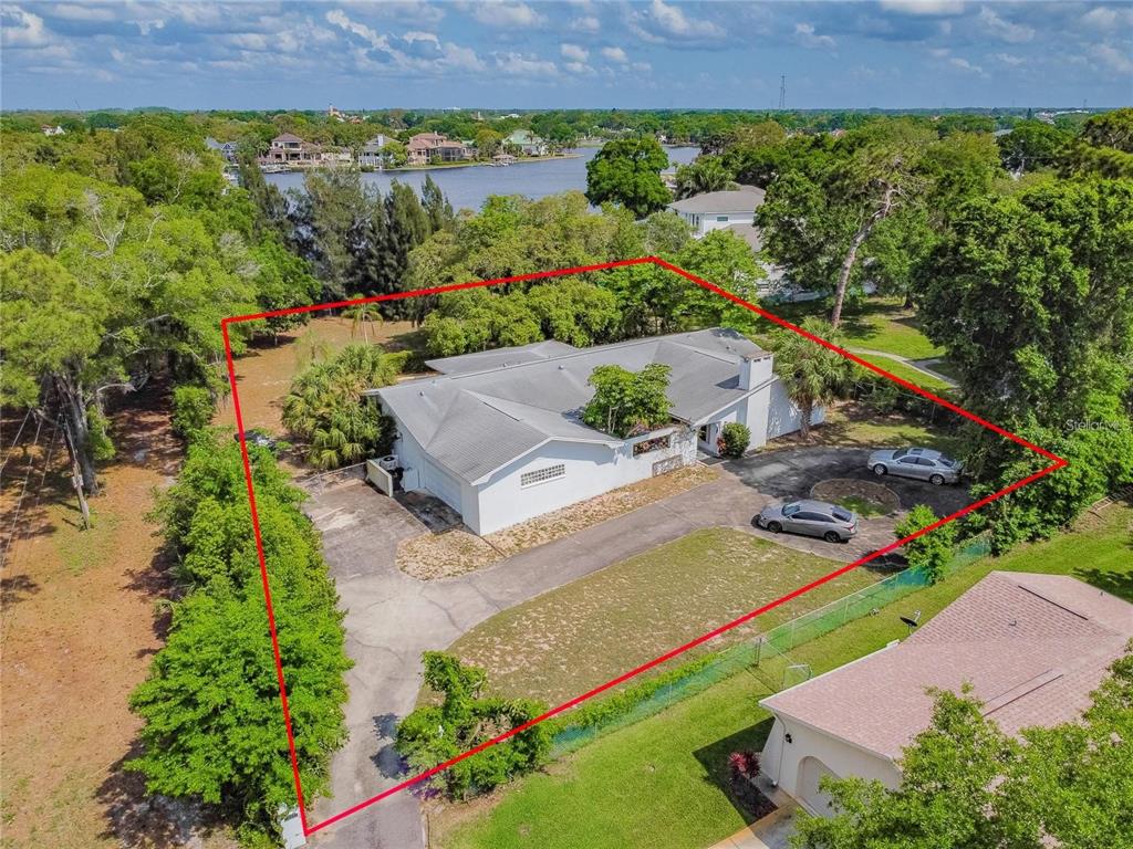 An aerial view shows a white house with a gray roof on a wooded lot — 425 CRAIG DRIVE, TARPON SPRINGS, FL