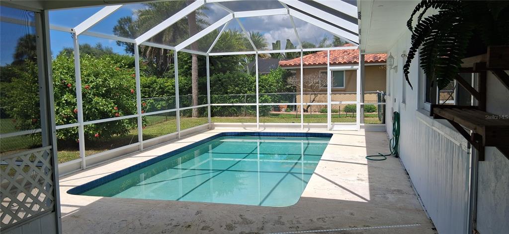 A rectangular swimming pool is enclosed by a white screen cage on a concrete patio — 441 RUBENS DRIVE E, NOKOMIS, FL