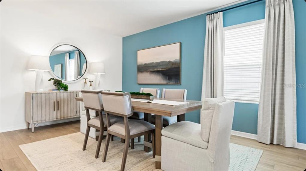 A dining room features a wooden table, upholstered chairs, a blue accent wall, and curtains — 5455 ISLA SAONA DRIVE, KISSIMMEE, FL