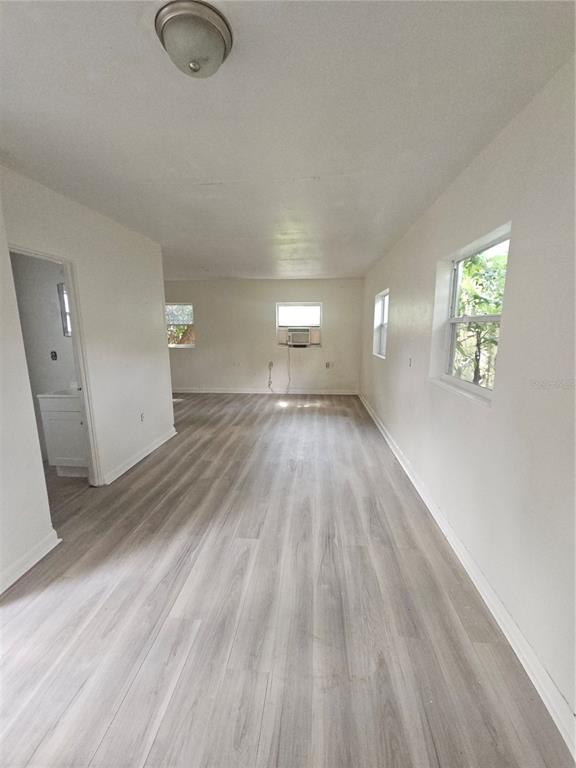 An empty room with light wood-look flooring, white walls, and a window air conditioning unit — 00 E WASHINGTON STREET UNIT Rear, ORLANDO, FL
