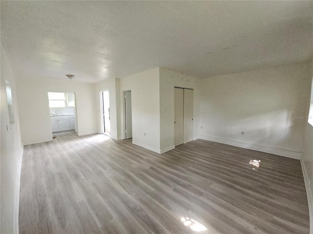 An interior view of a room with light wood-look flooring, white walls, and a closet — 00 E WASHINGTON STREET UNIT Rear, ORLANDO, FL