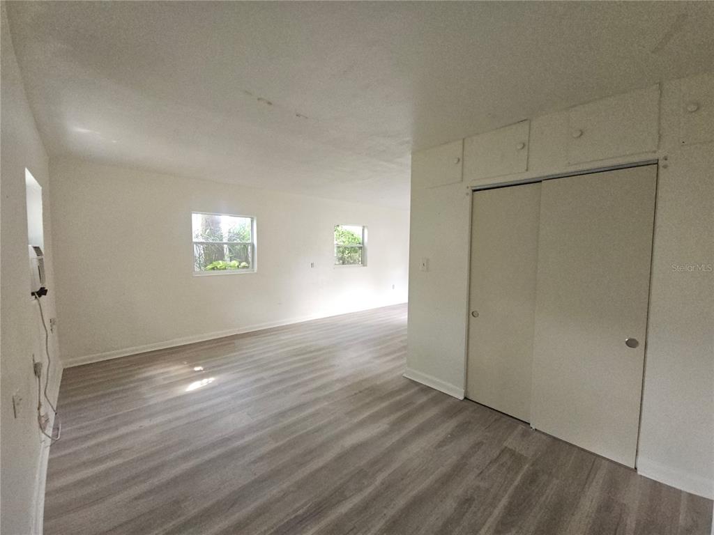 An empty room features light wood-look flooring, white walls, two windows, and a sliding closet — 00 E WASHINGTON STREET UNIT Rear, ORLANDO, FL
