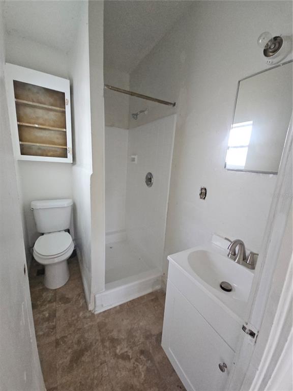A small bathroom featuring a white vanity, a standing shower stall, and a white toilet — 00 E WASHINGTON STREET UNIT Rear, ORLANDO, FL