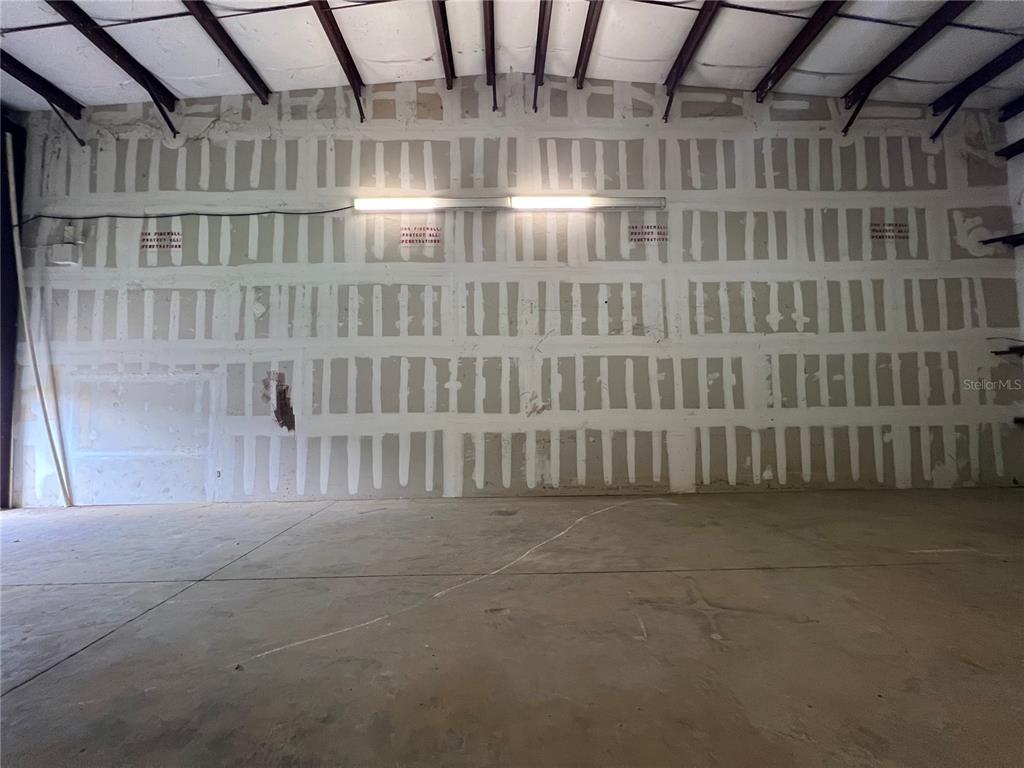 An unfinished warehouse interior features exposed metal ceiling beams and drywall with taped seams — 7216 CHANCERY UNIT 200, ORLANDO, FL