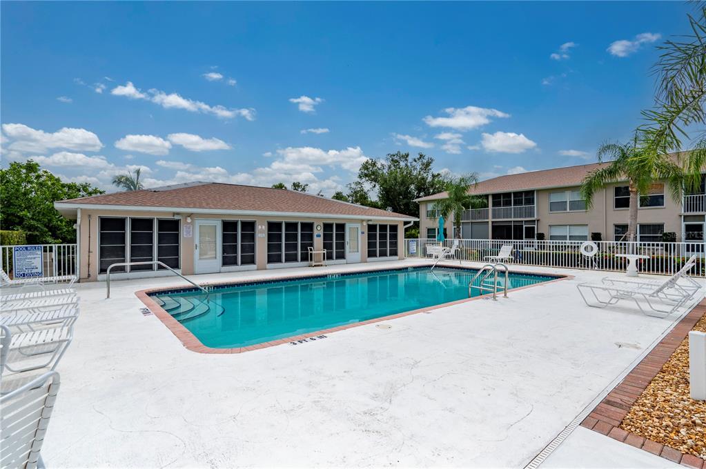 A rectangular swimming pool sits on a concrete deck in front of a residential building — 11644 SW EGRET CIRCLE UNIT 908, LAKE SUZY, FL