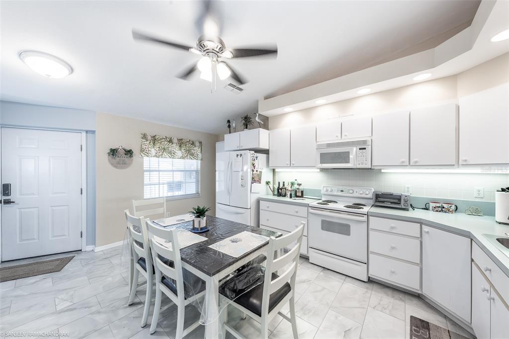 A kitchen with white cabinets, a dining table, and light-colored tile flooring — 11644 SW EGRET CIRCLE UNIT 908, LAKE SUZY, FL