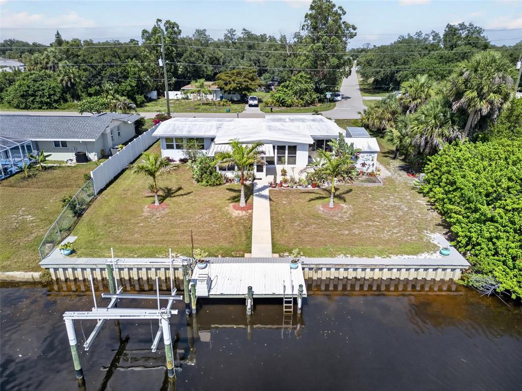An aerial view shows a waterfront house with a dock, boat lift, and palm trees — 3349 ROCK CREEK DRIVE, PORT CHARLOTTE, FL
