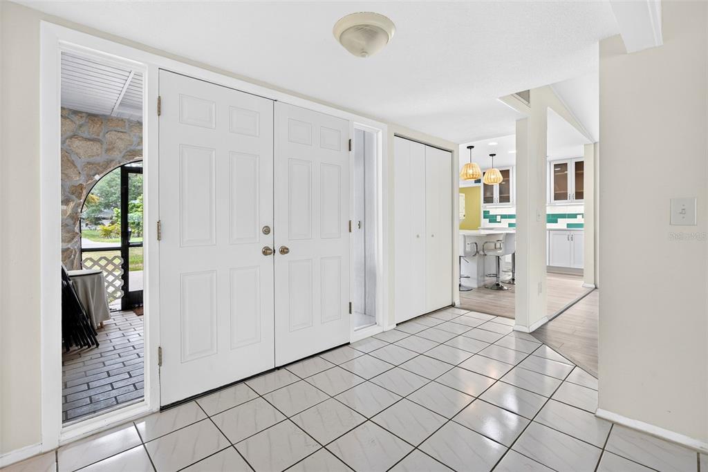 A tiled entryway features double white doors, a coat closet, and a view into a kitchen — 3349 ROCK CREEK DRIVE, PORT CHARLOTTE, FL