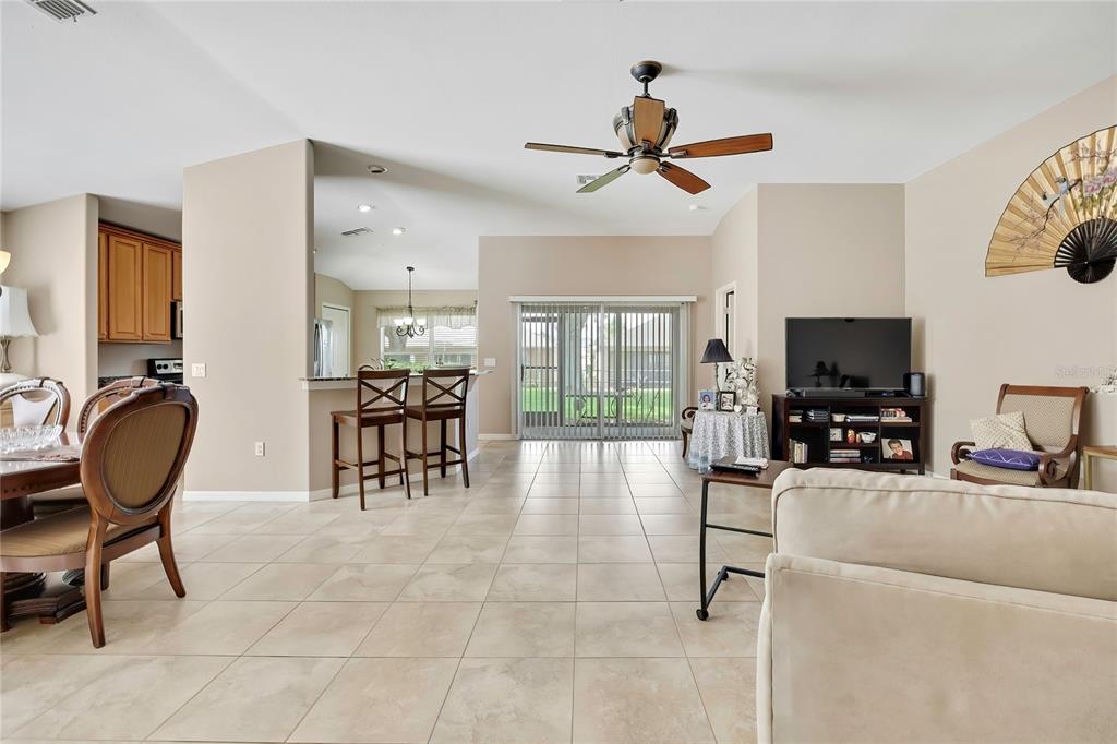 A living room with tile floors, a ceiling fan, and an open kitchen with bar seating — 11910 HERITAGE POINT DRIVE, HUDSON, FL
