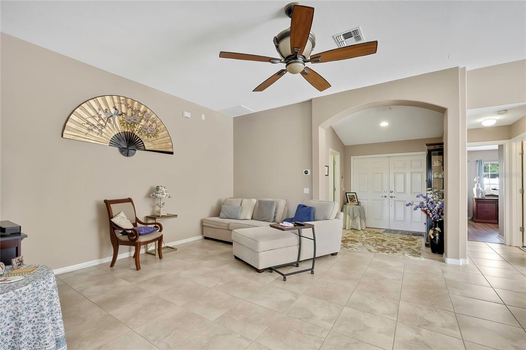 A living room with beige walls, tile flooring, a ceiling fan, and a sectional sofa — 11910 HERITAGE POINT DRIVE, HUDSON, FL