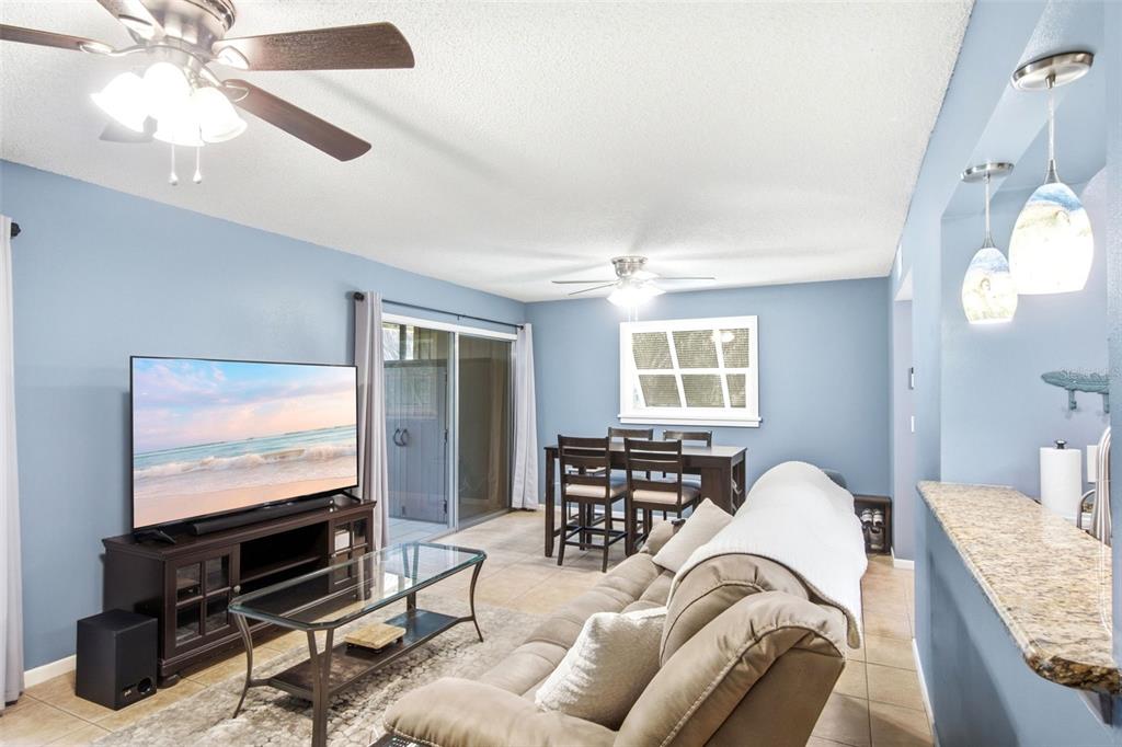 A living room and dining area with blue walls, tile floors, and a ceiling fan — 140 ORCHID WOODS COURT UNIT 1B, DELTONA, FL