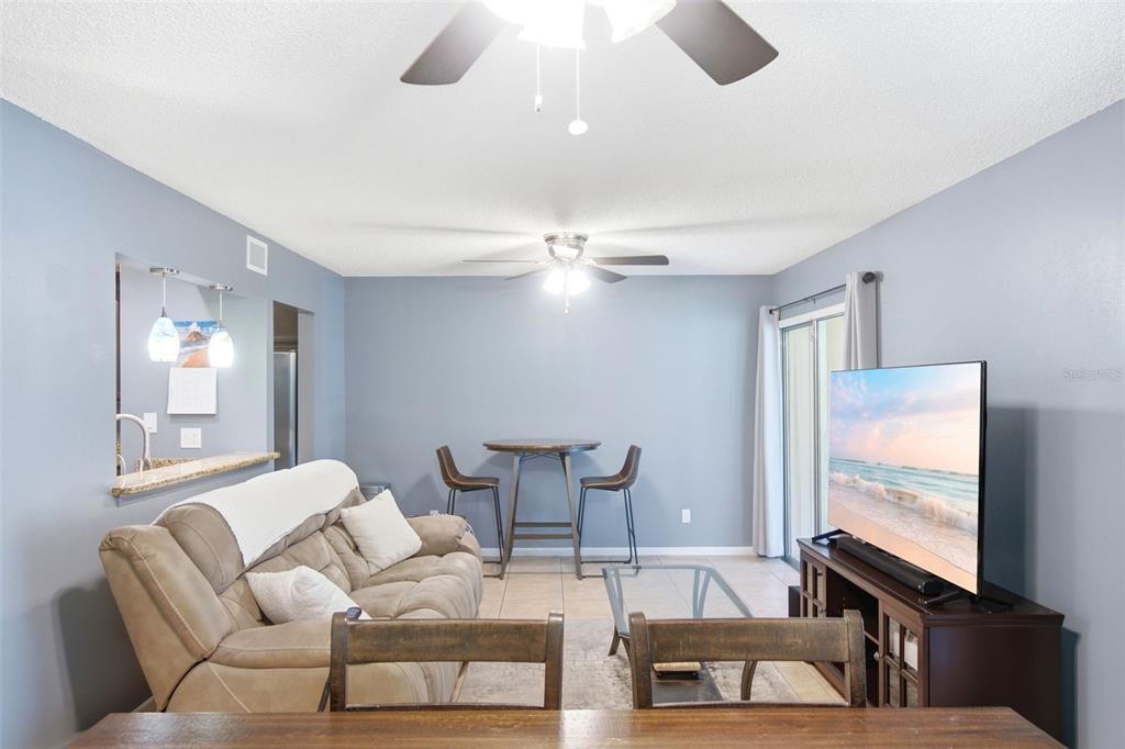 A living room features a beige sofa, a small dining table, and a television console — 140 ORCHID WOODS COURT UNIT 1B, DELTONA, FL