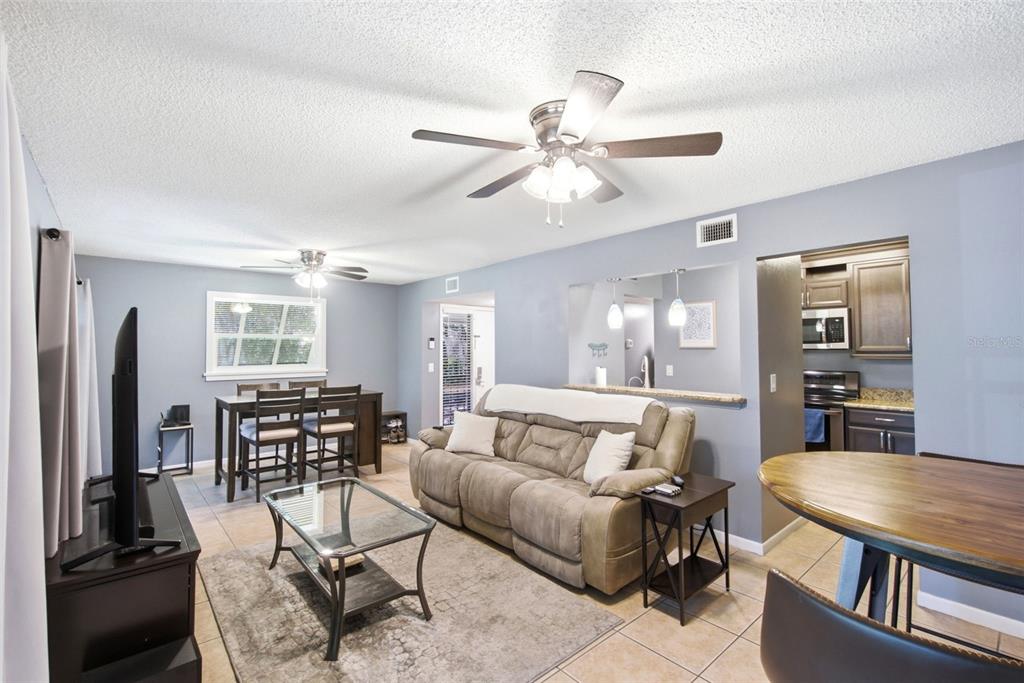 A living room with a sofa, coffee table, dining set, and an open kitchen pass-through — 140 ORCHID WOODS COURT UNIT 1B, DELTONA, FL