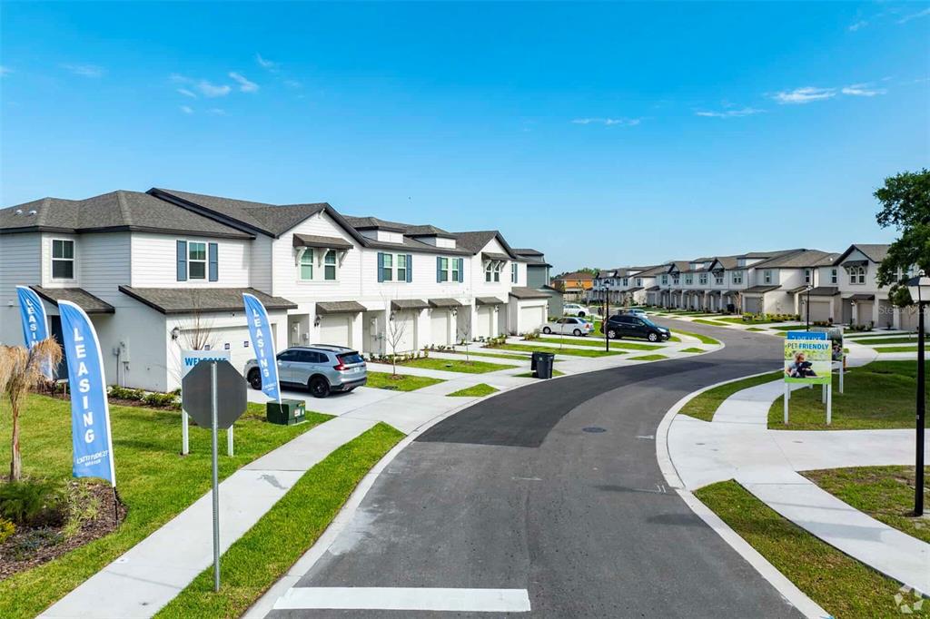 A street view of a residential complex featuring multi-unit townhomes with white siding and garages — 8683 HOLLY GROVE COURT UNIT Oakville, RIVERVIEW, FL