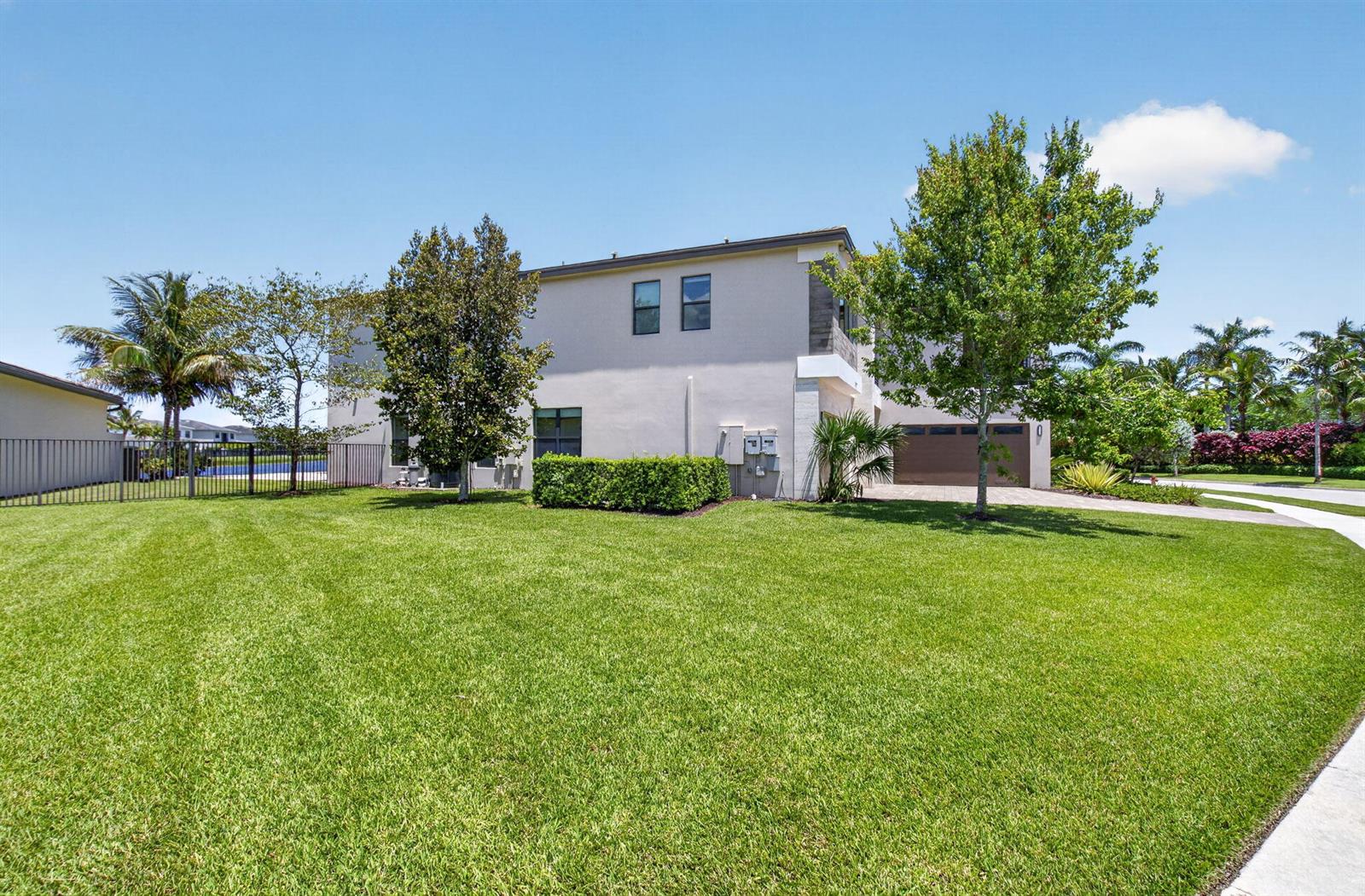 A two-story house with a large green lawn, a driveway, and surrounding trees — 17100 Wandering Wave Avenue, Boca Raton FL 33496, BOCA RATON, FL